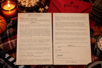 A Rainy Day Film Society letter from the host, signed by Jennifer, laid out beside a red envelope, popcorn and candles
